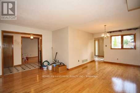A room with wooden floors and white walls, with a door on the left and a window on the right.