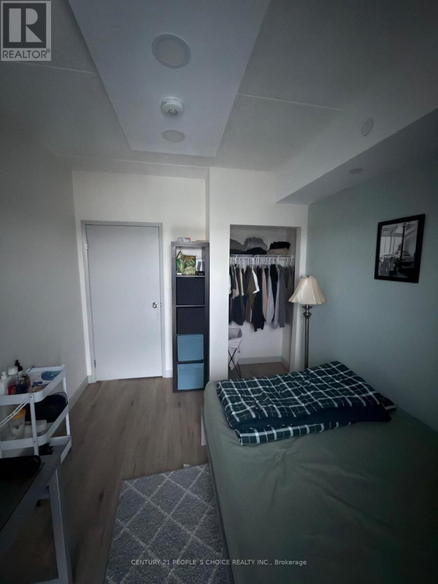 A bedroom with a bed, a nightstand with a lamp, and a closet with clothes.