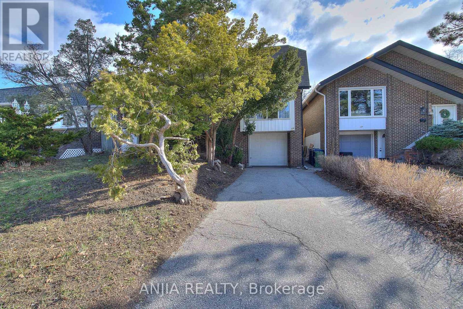 A house with a driveway and a tree in front of it.