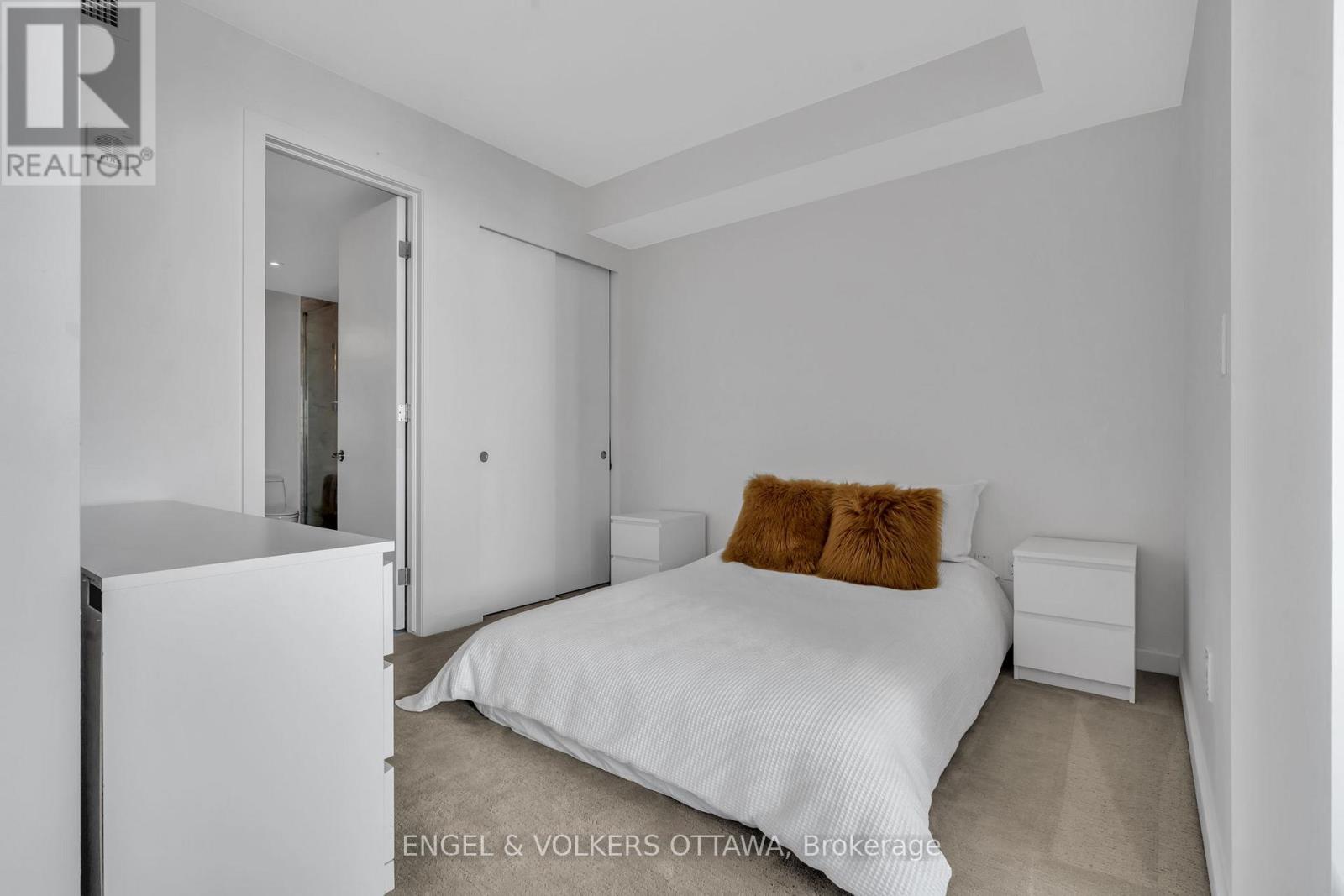 A bedroom with a white bed and two brown pillows.