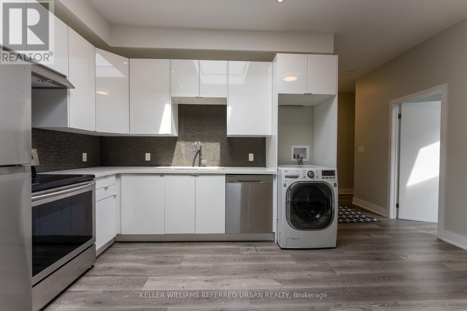 A modern kitchen with white cabinets and stainless steel appliances.