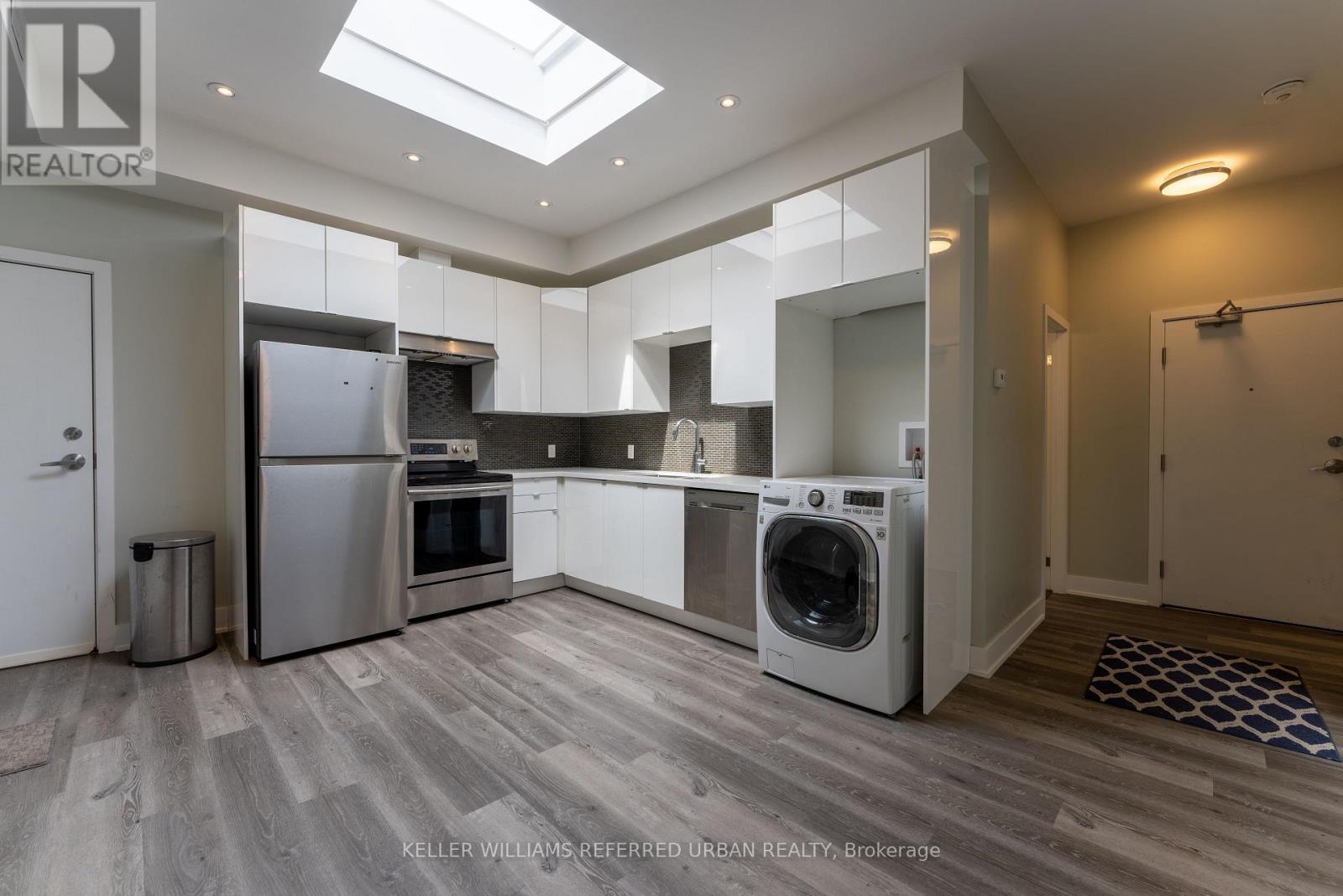 A modern kitchen with a skylight and a washer and dryer built in.