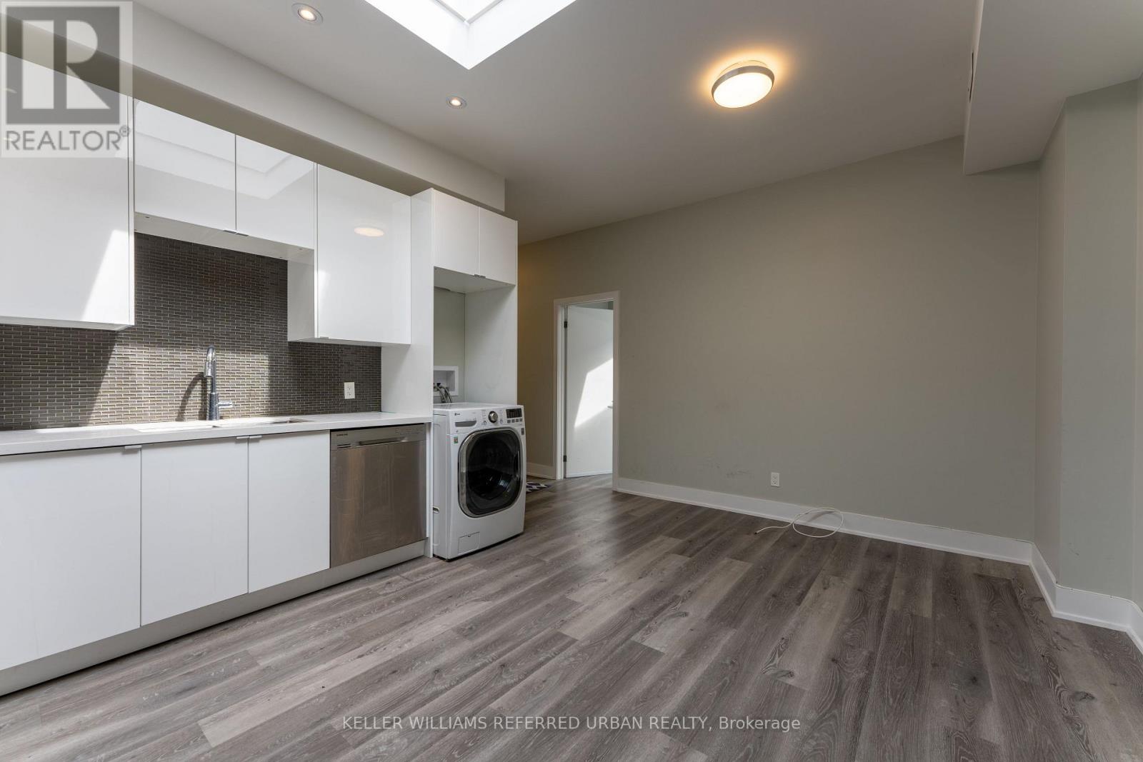 A spacious kitchen with white cabinets and a wooden floor.