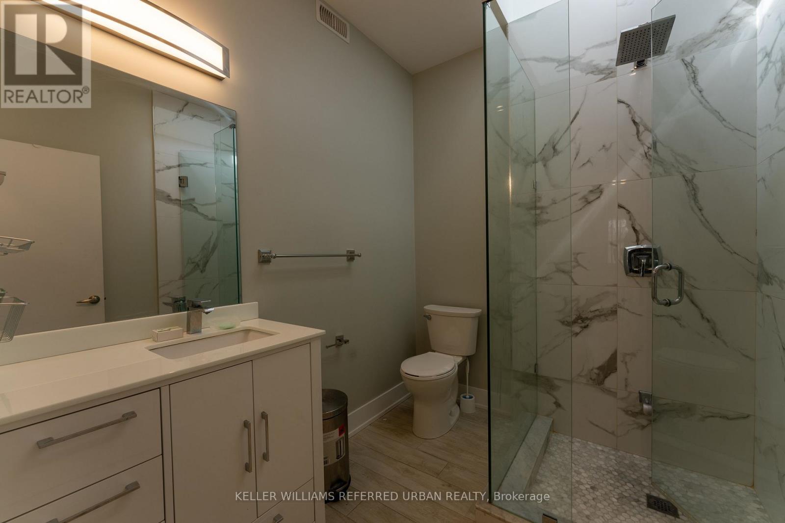 A bathroom with a marble shower and toilet.