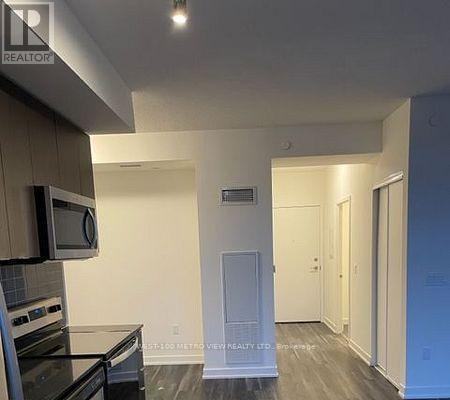 A kitchen area with a microwave, oven, and a fridge.