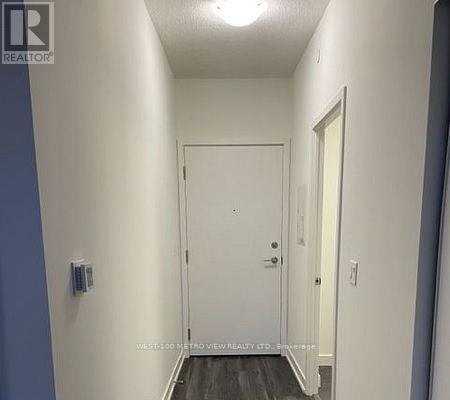 A hallway with a white door and a light switch on the wall.