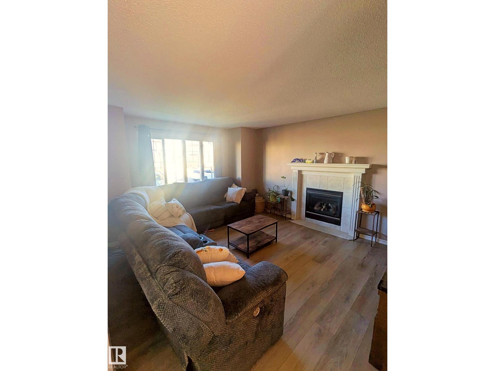 A living room with a grey couch and a fireplace.