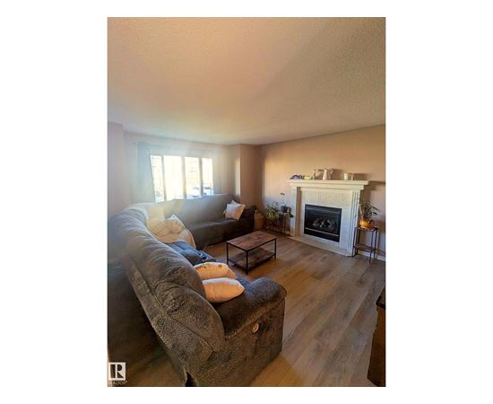 A living room with a grey couch and a fireplace.