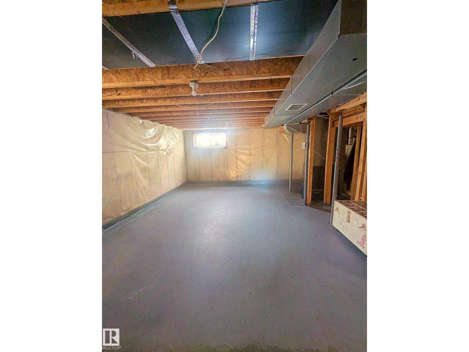 A spacious unfinished basement with a concrete floor and exposed ceiling.