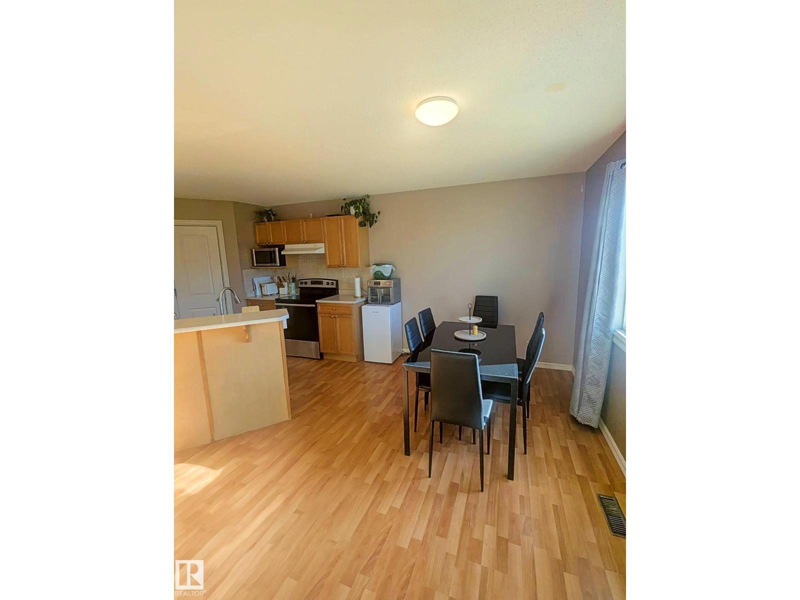 A kitchen with a dining table and chairs.