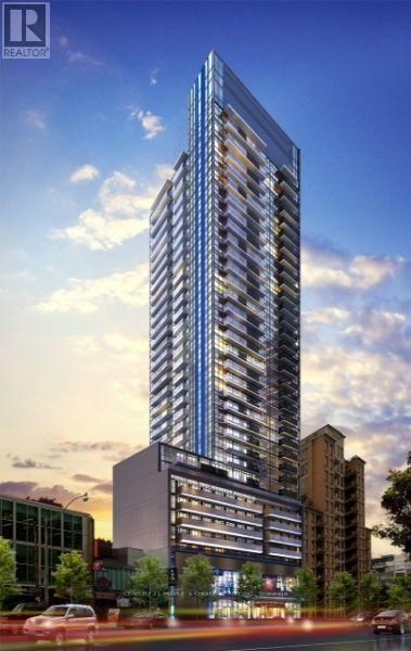 A tall, modern glass building stands in the foreground of a city street.