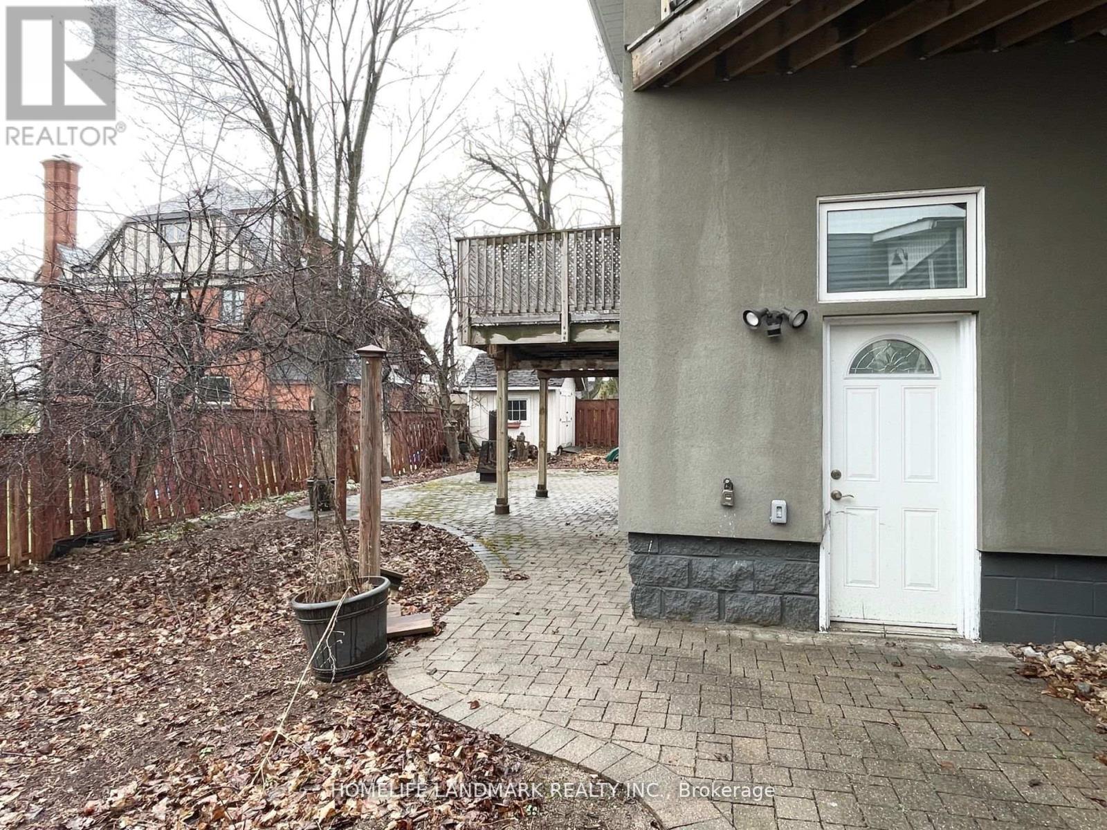 A house with a white door is surrounded by a brick walkway and a fence.