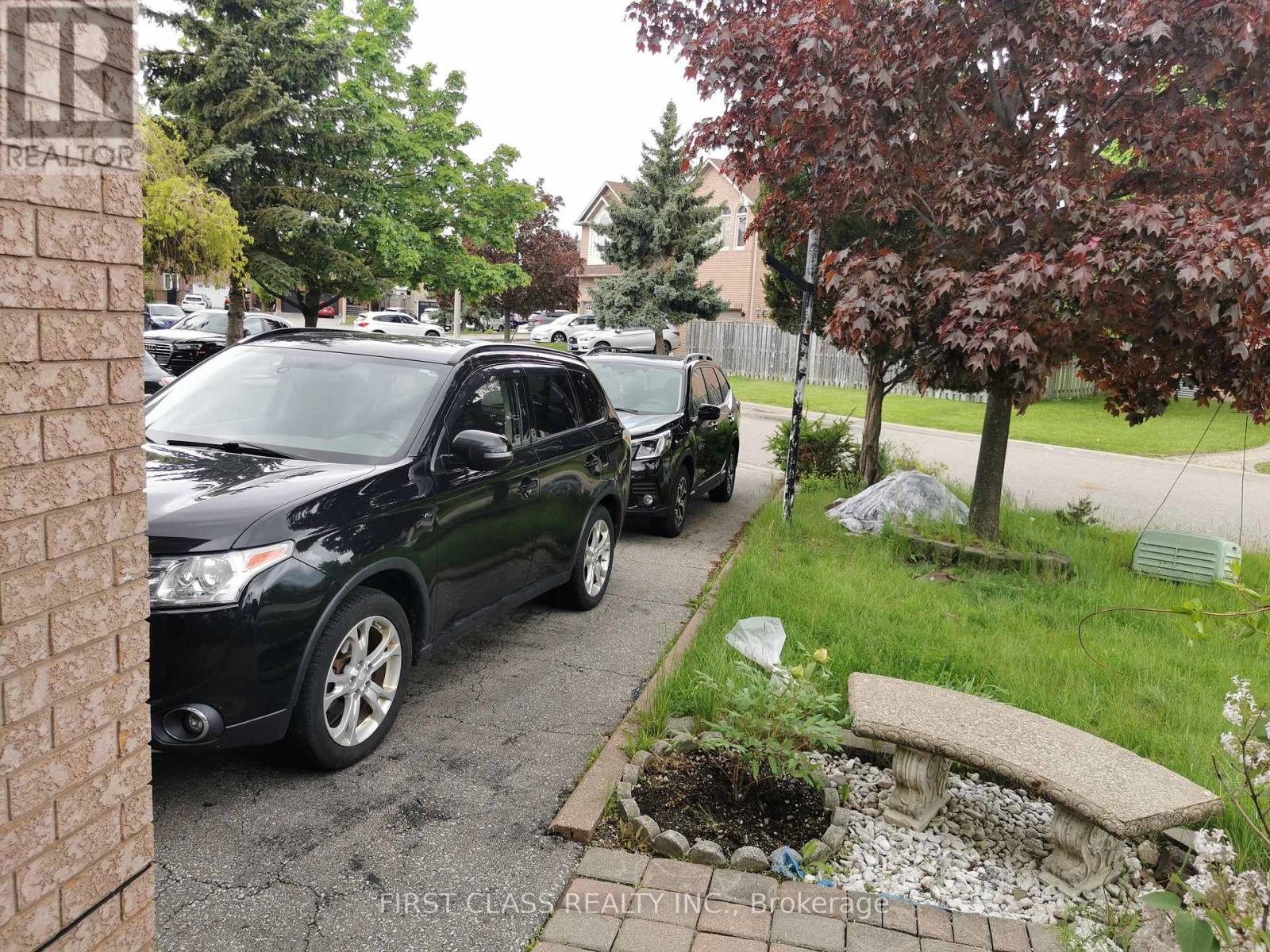 A black car is parked on a driveway.