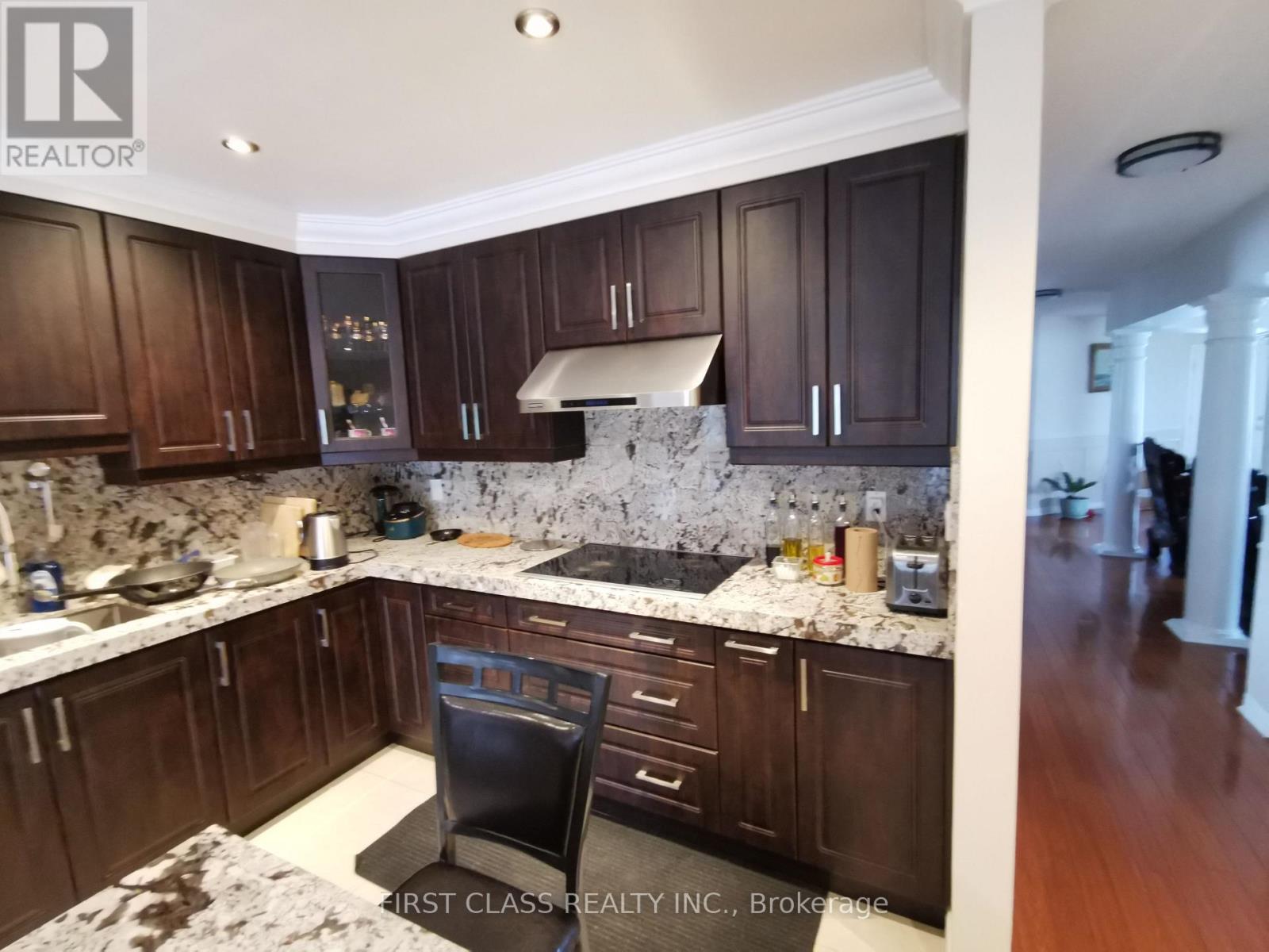 A kitchen with dark wood cabinets and a marble countertop.