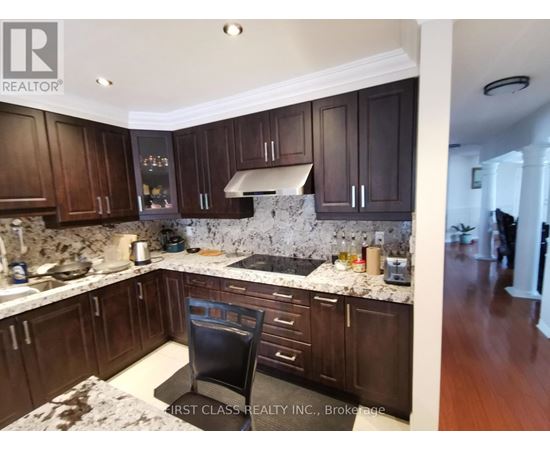A kitchen with dark wood cabinets and a marble countertop.