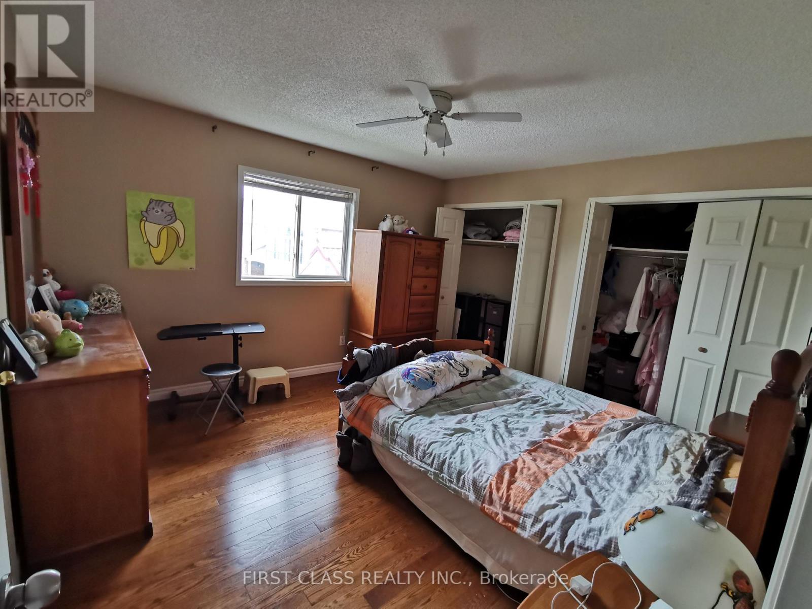 A bedroom with a bed, dresser, and a ceiling fan.