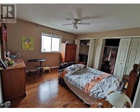 A bedroom with a bed, dresser, and a ceiling fan.