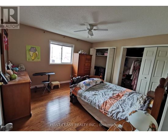 A bedroom with a bed, dresser, and a ceiling fan.