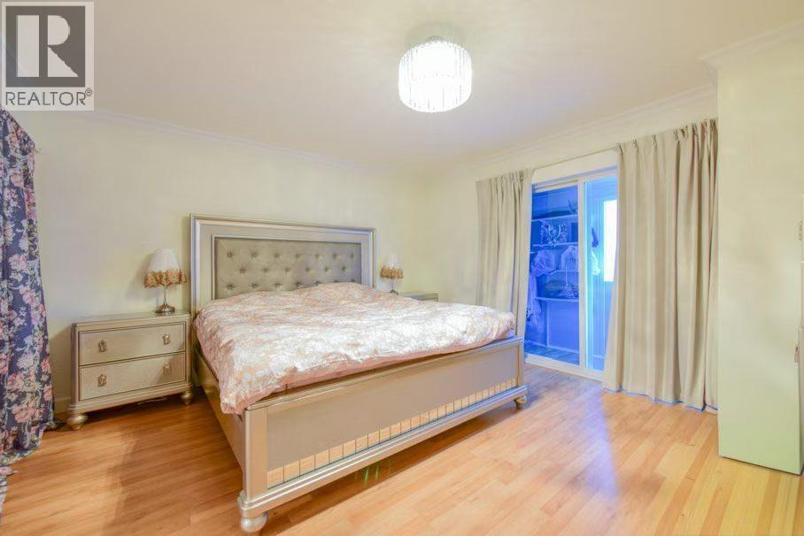 A bedroom with a large bed, a nightstand, and a window with curtains.
