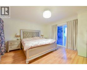 A bedroom with a large bed, a nightstand, and a window with curtains.