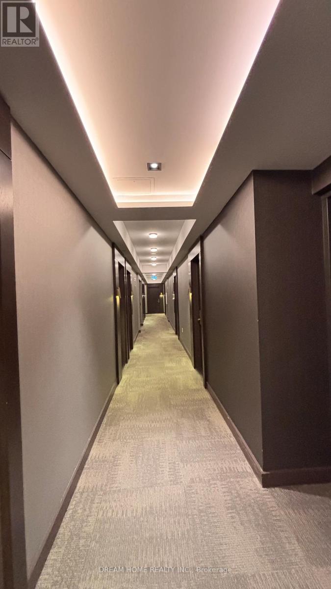 A long, narrow hallway with a carpeted floor and walls on either side.