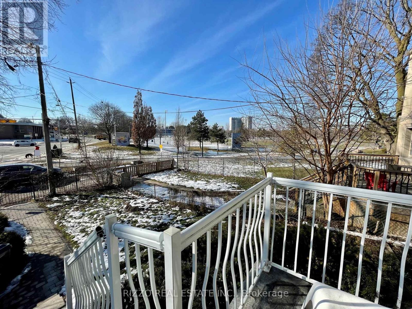 A white railing with a view of a snowy landscape and buildings in the distance.