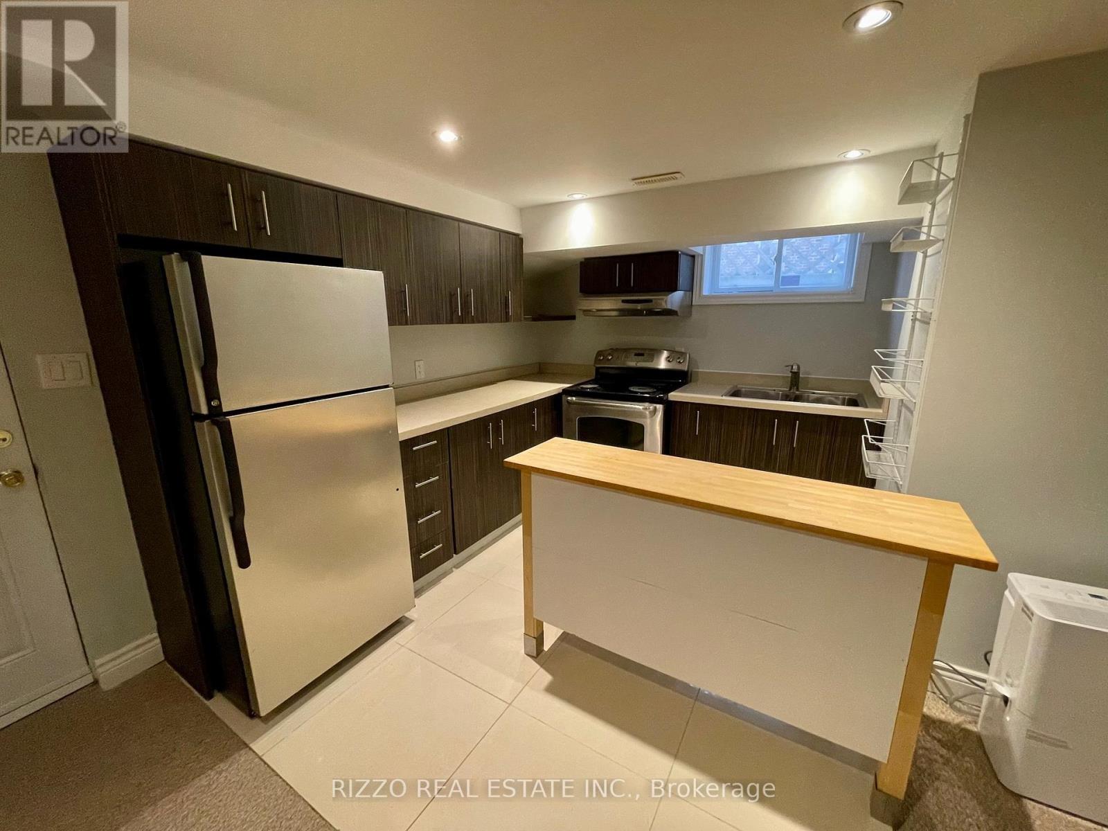 A kitchen with a refrigerator, oven, and sink.