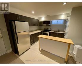 A kitchen with a refrigerator, oven, and sink.