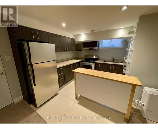 A kitchen with a refrigerator, oven, and sink.