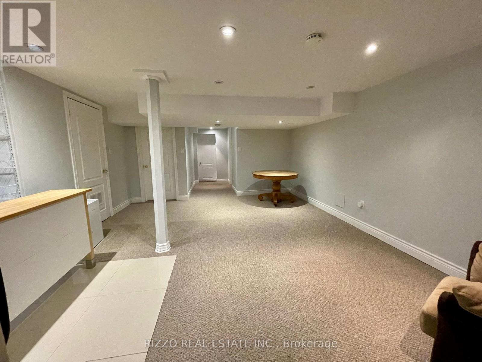 A spacious room with a carpeted floor and a wooden table in the middle.