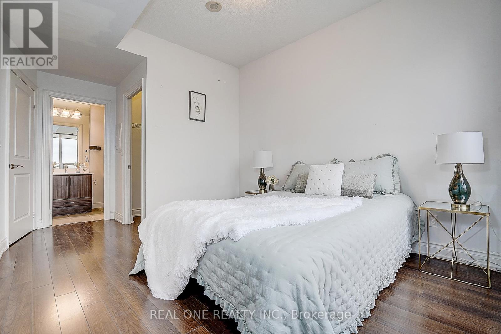 A bedroom with a large bed and a nightstand with a lamp.