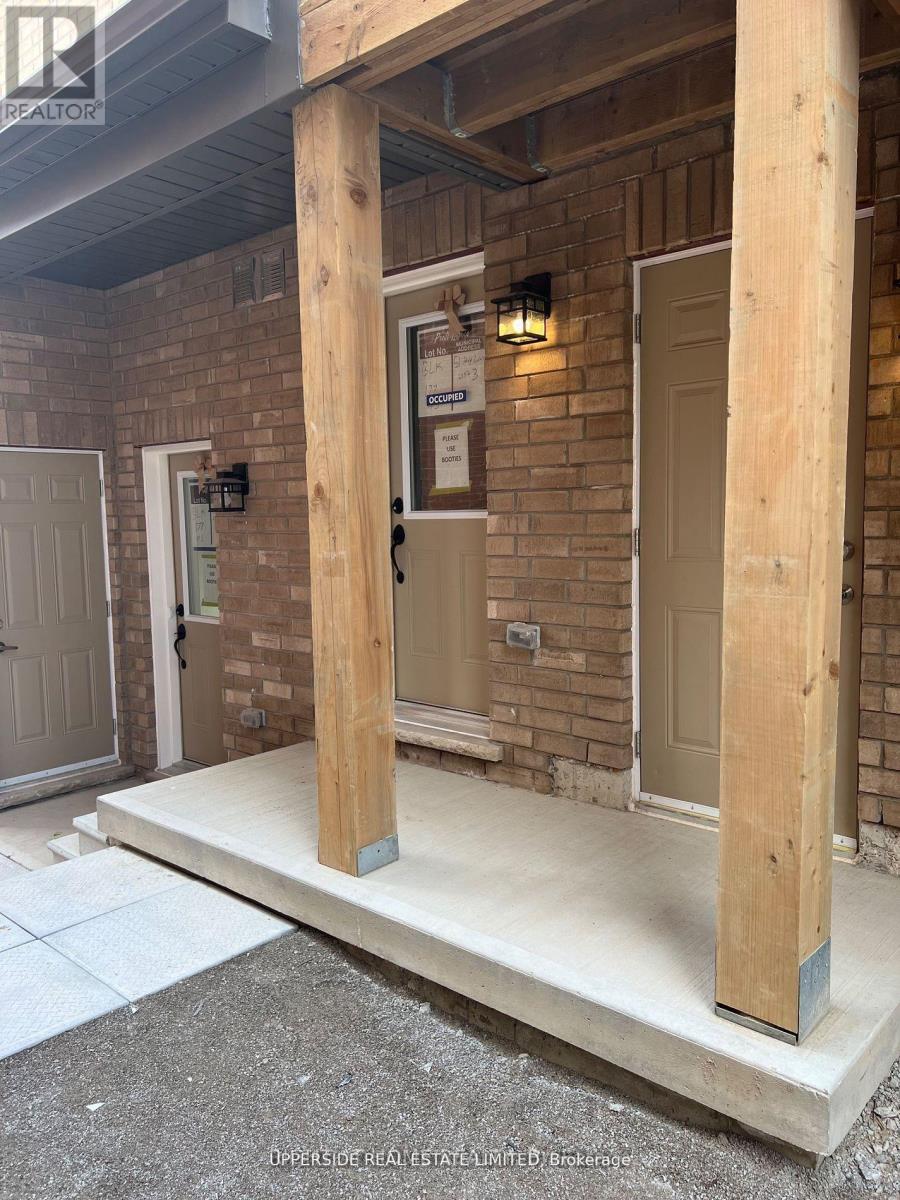 A wooden porch with a white door and a brick wall.