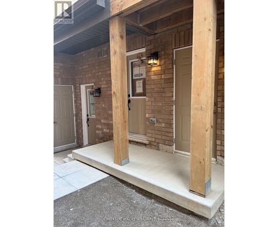 A wooden porch with a white door and a brick wall.
