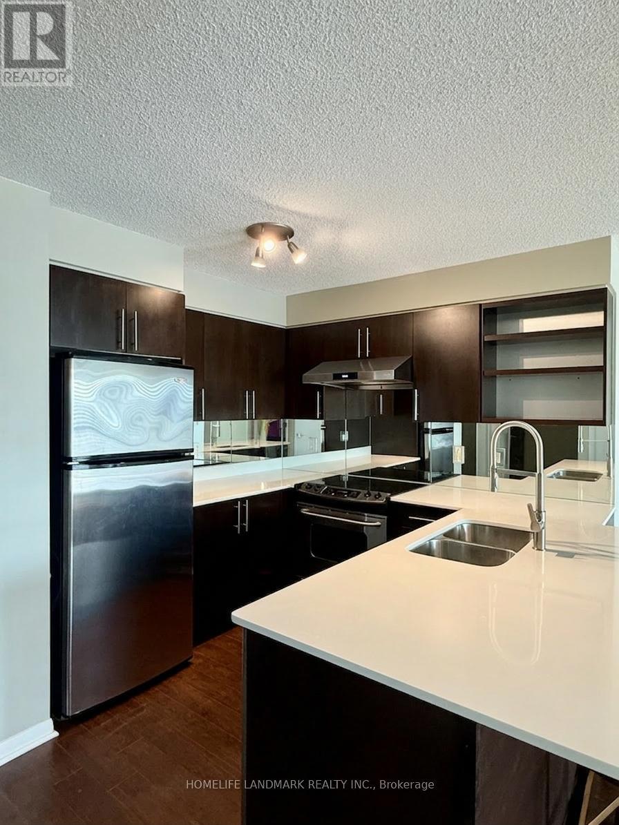 A modern kitchen with dark wood cabinets and stainless steel appliances.