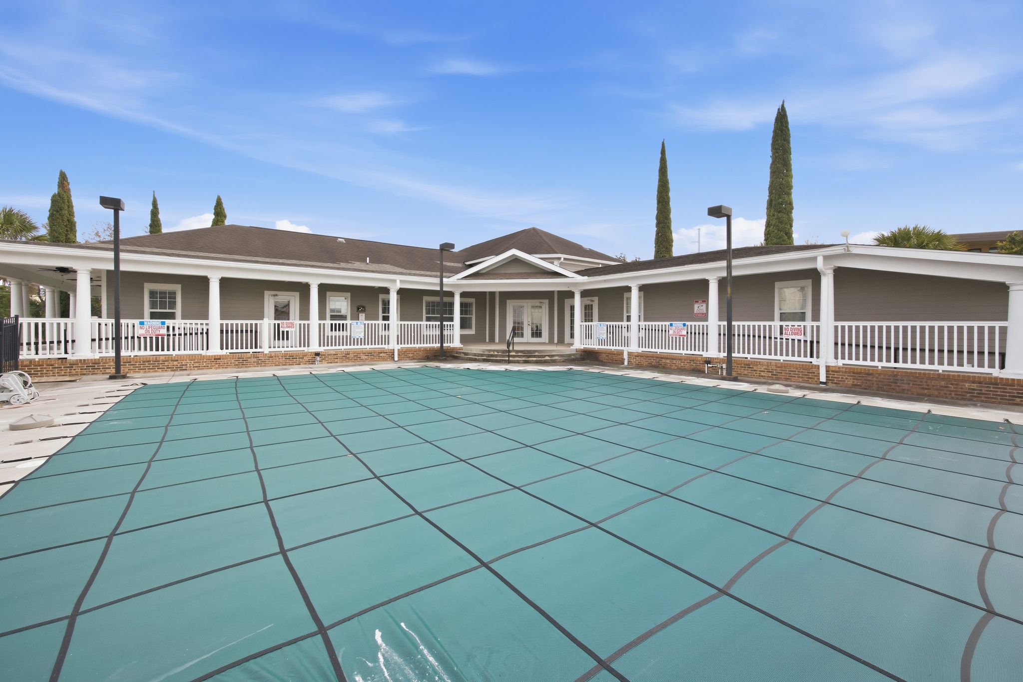 A large swimming pool in front of a building with a white fence around it.