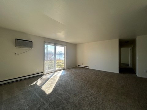 A room with a carpeted floor and a window with blinds.