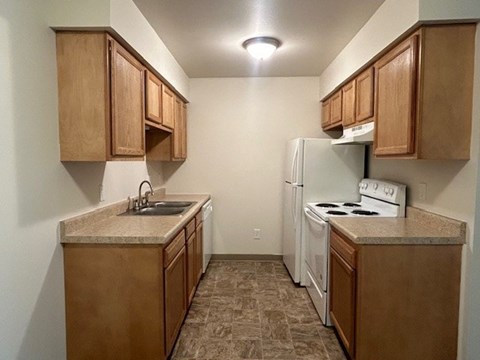 A kitchen with brown cabinets and a white refrigerator.