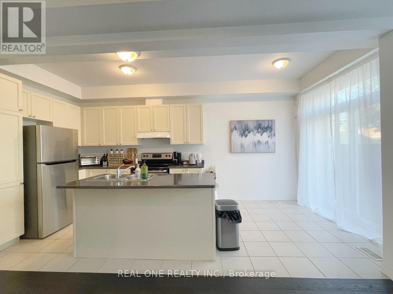 A kitchen with white cabinets and a stainless steel refrigerator.