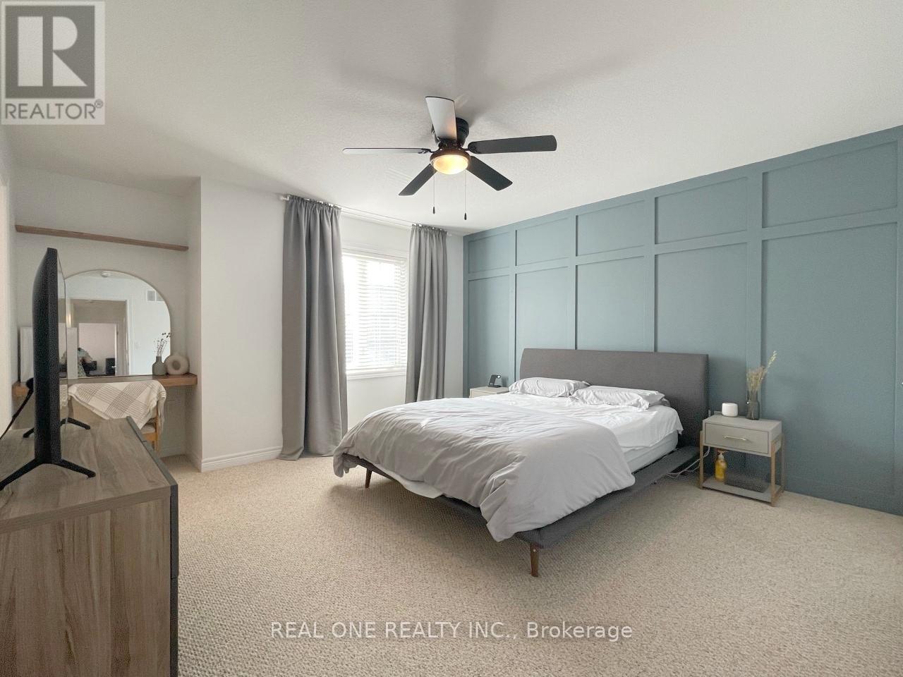 A bedroom with a bed, a ceiling fan, and a nightstand.