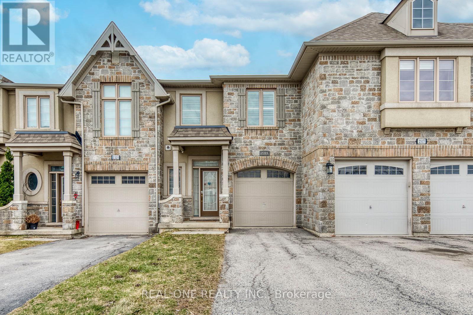 A large, two-story house with a stone facade and multiple garages.
