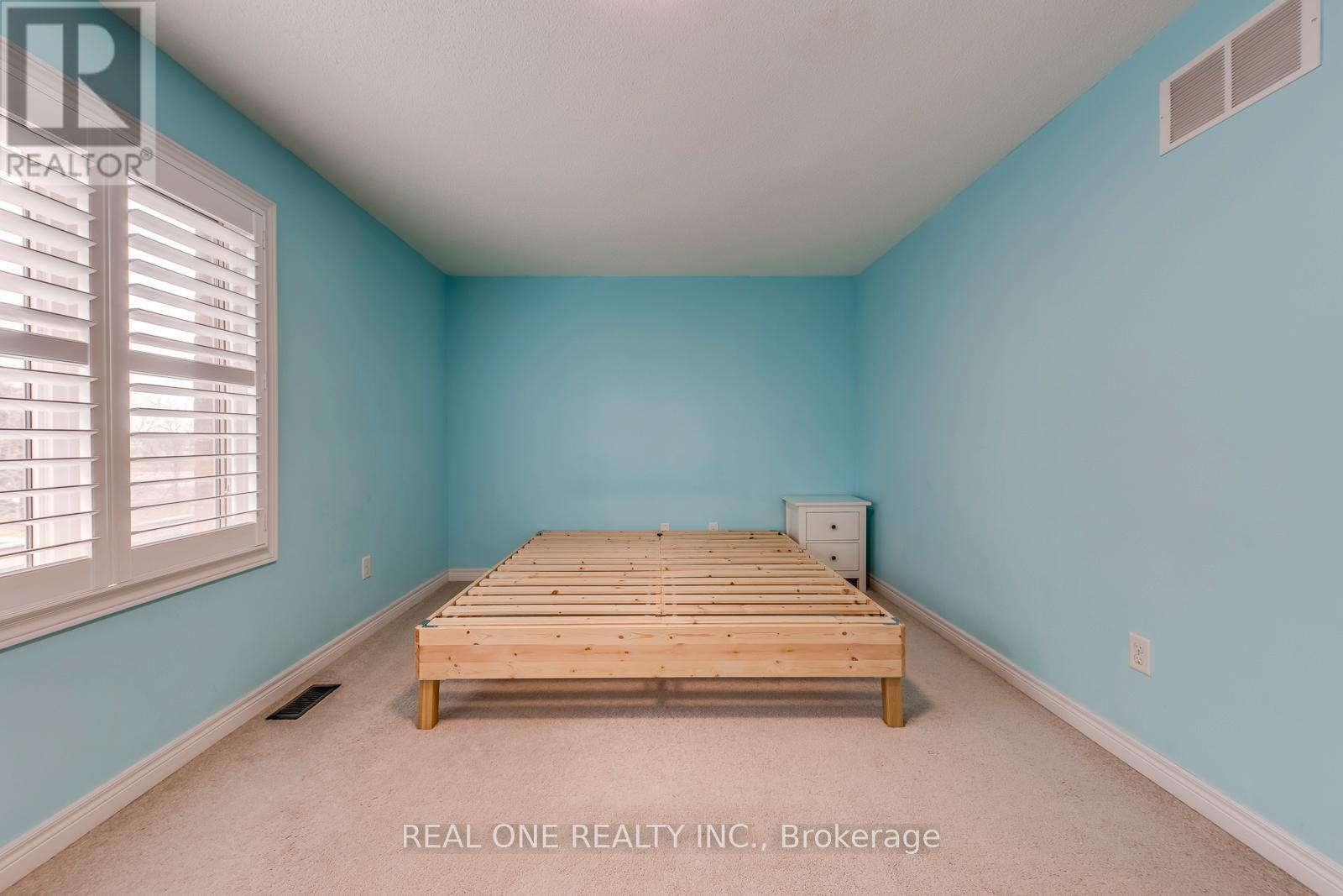 A bedroom with a bed frame in the middle of the room.