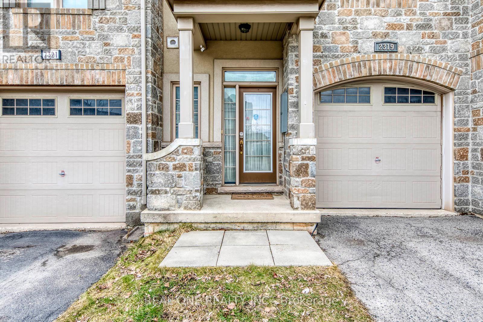 A stone building with a brown door and two garage doors.
