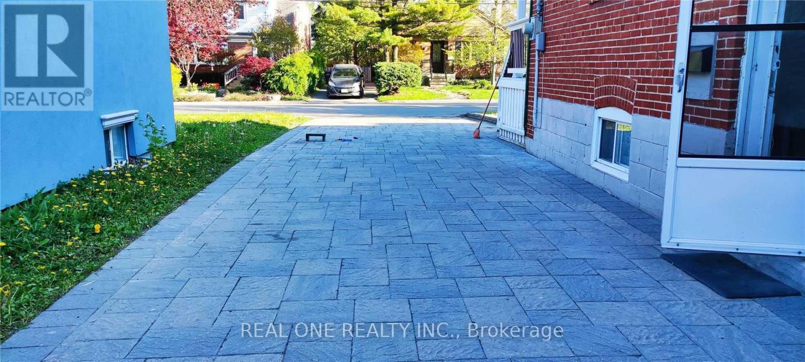 A sidewalk in front of a brick building with a REALTOR sign.