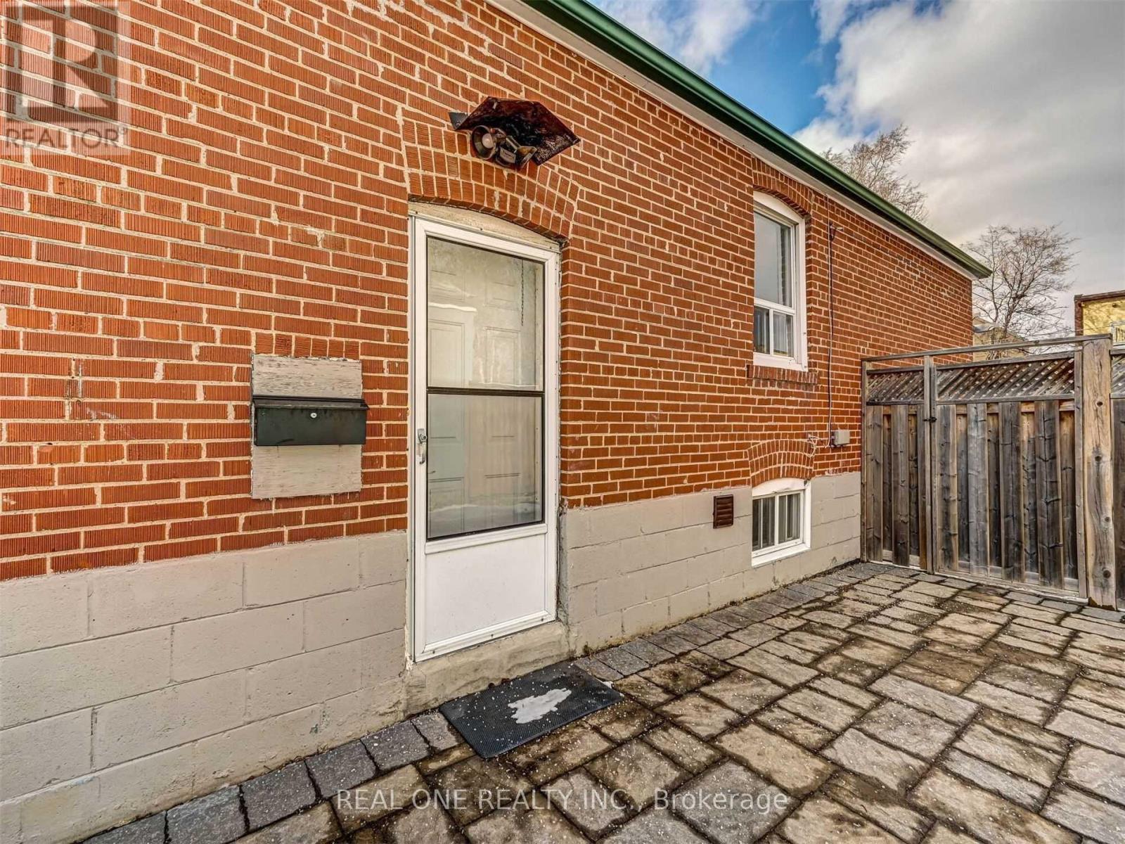 A brick house with a white door and a small window above it.