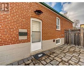 A brick house with a white door and a small window above it.