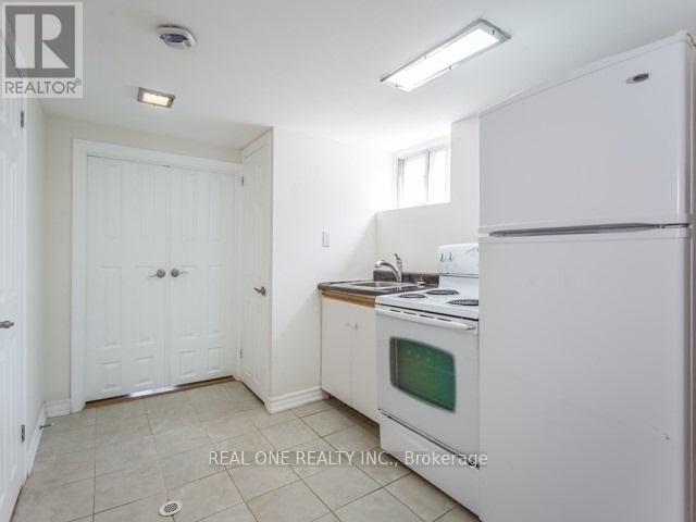 A white kitchen with a fridge, oven and microwave.