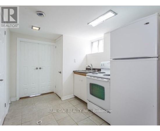 A white kitchen with a fridge, oven and microwave.