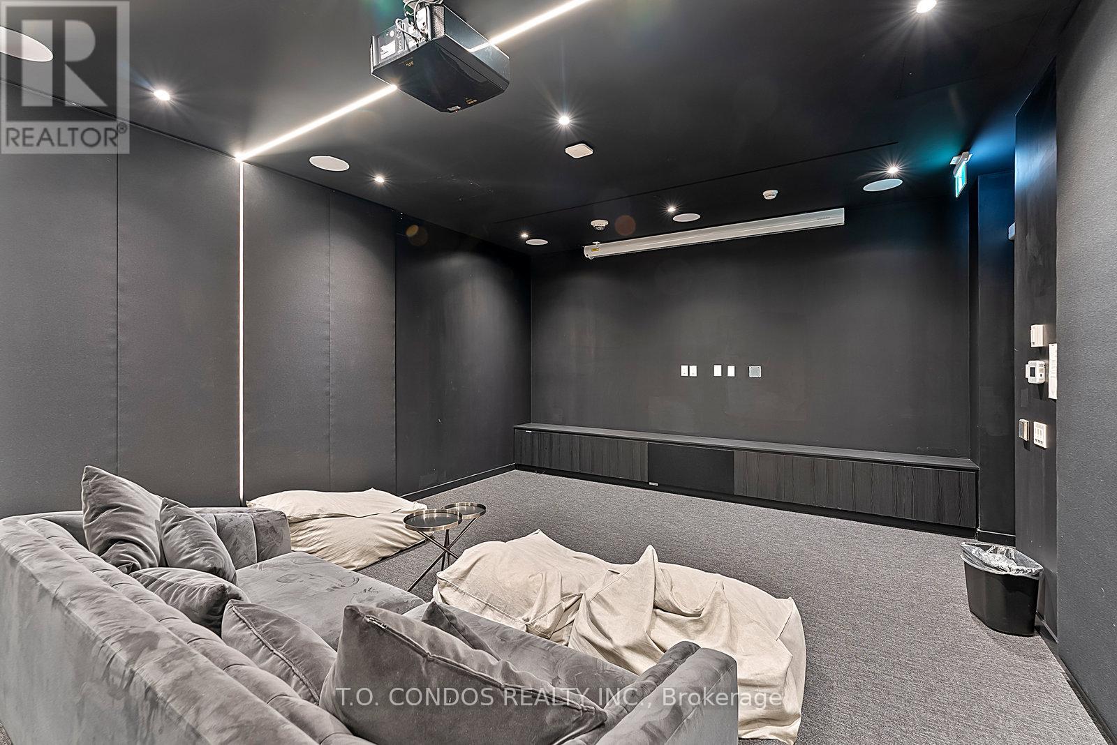 A modern living room with a grey couch and a black wall.