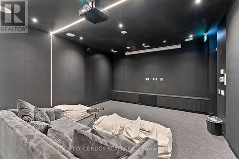 A modern living room with a grey couch and a black wall.