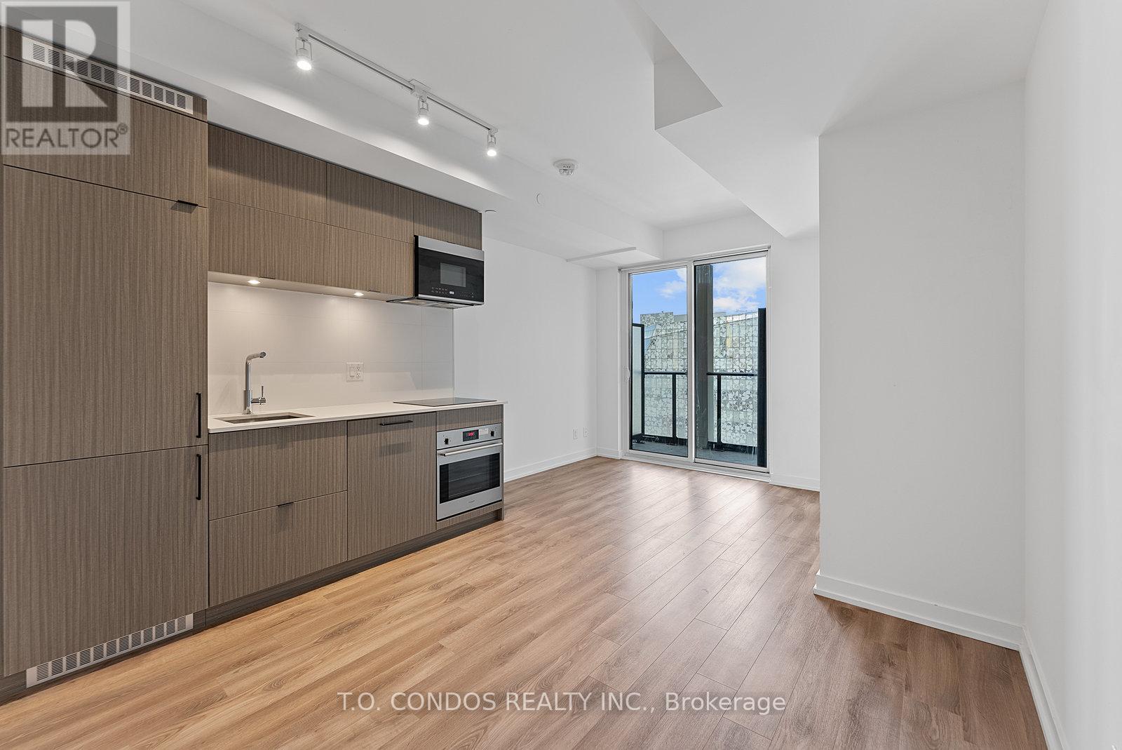 A modern kitchen with wooden cabinets and a large window.